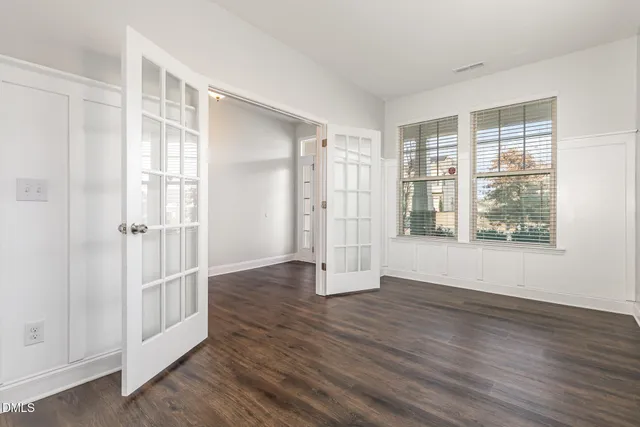 an empty room with wooden floor and windows