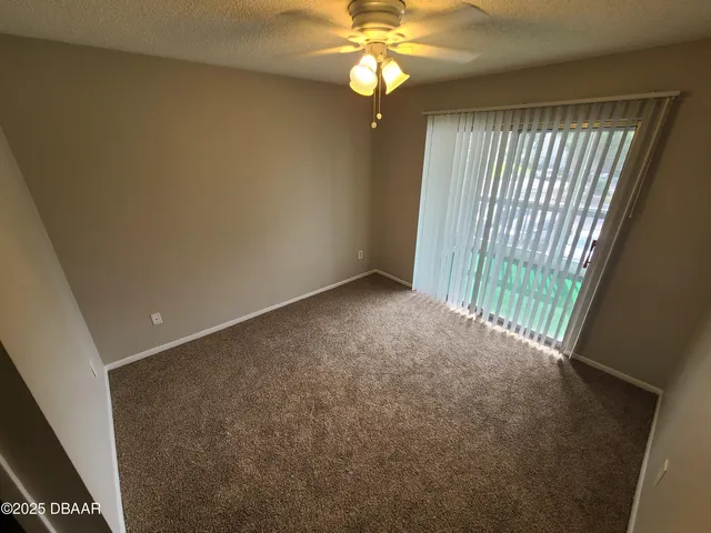 an empty room with windows and fan