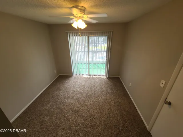 an empty room with a chandelier fan and closet