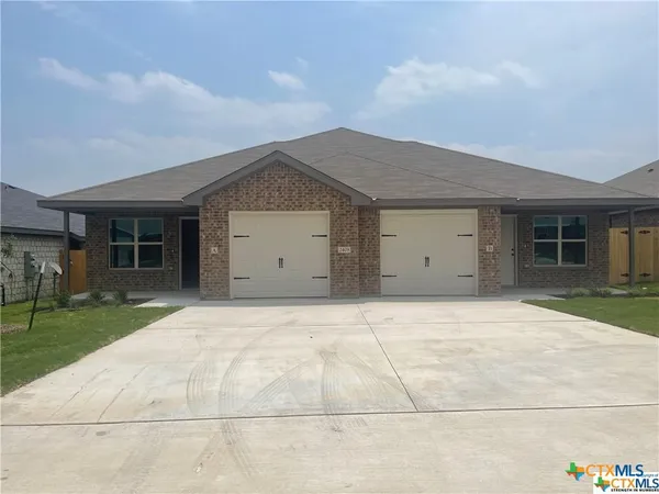front view of house with a yard and potted plants