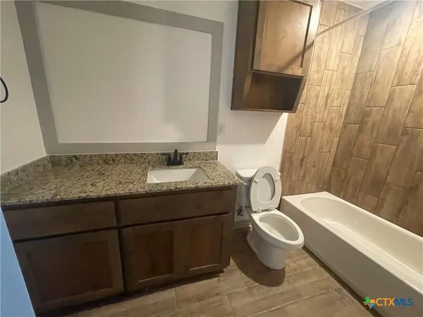 a bathroom with a granite countertop toilet sink and mirror