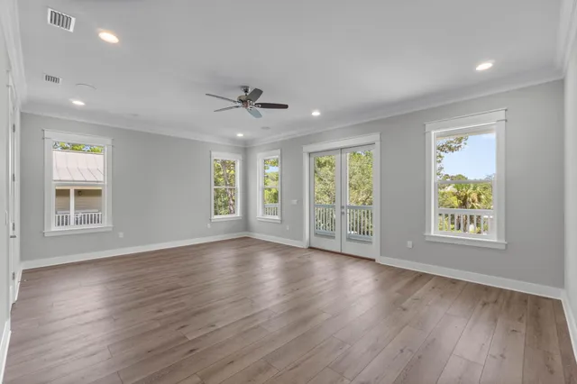 a view of an empty room with wooden floor and a ceiling fan