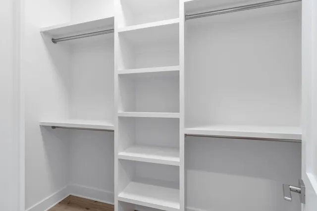an empty room with wooden floor closet and windows