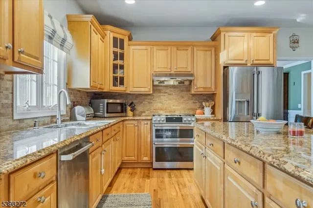 a kitchen with stainless steel appliances granite countertop a stove a sink and a microwave