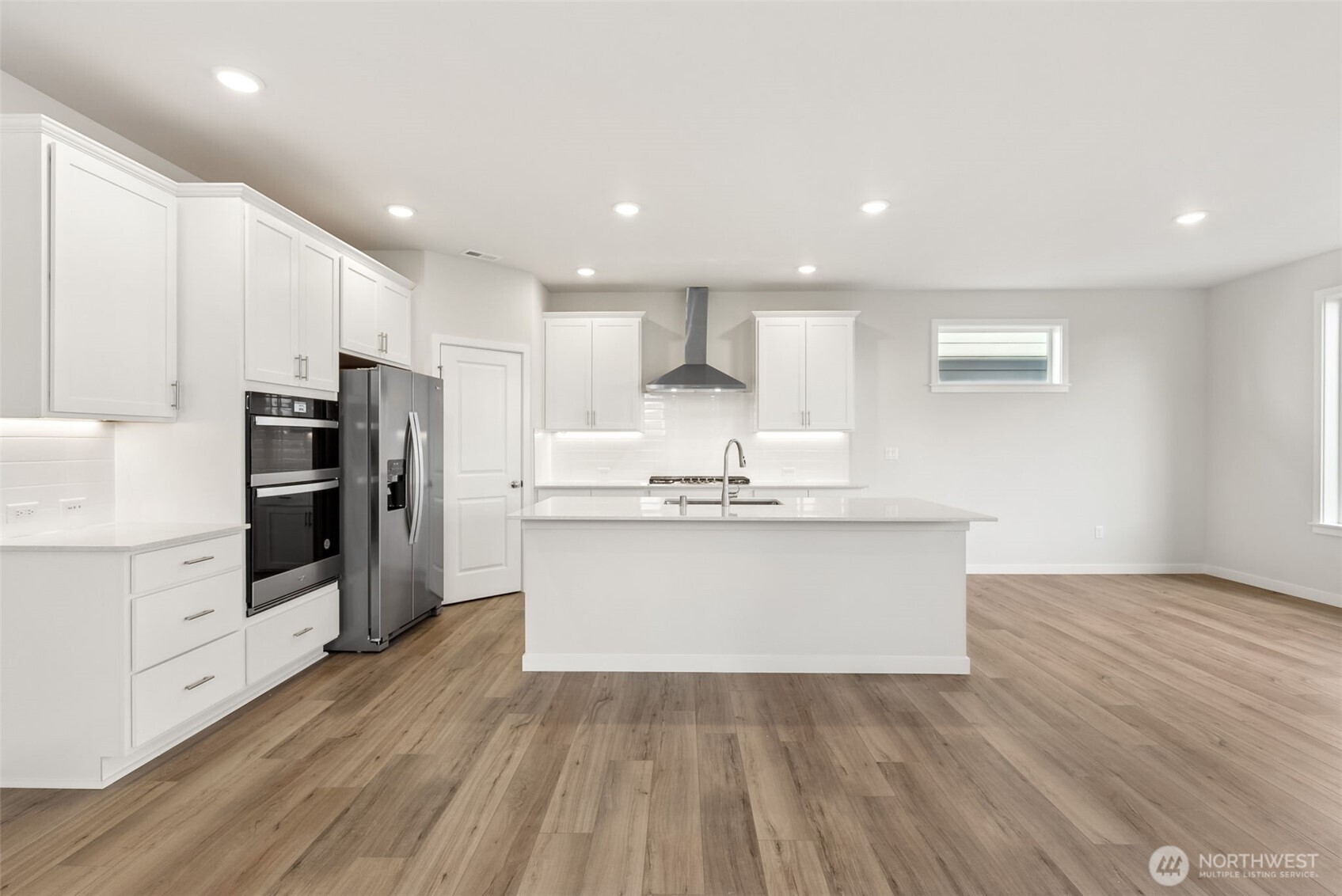 2064 Northeast Norseman Way Poulsbo, WA 98370 - Photo 9 of 28 a view of kitchen with granite countertop refrigerator oven a sink and white cabinets with wooden floor