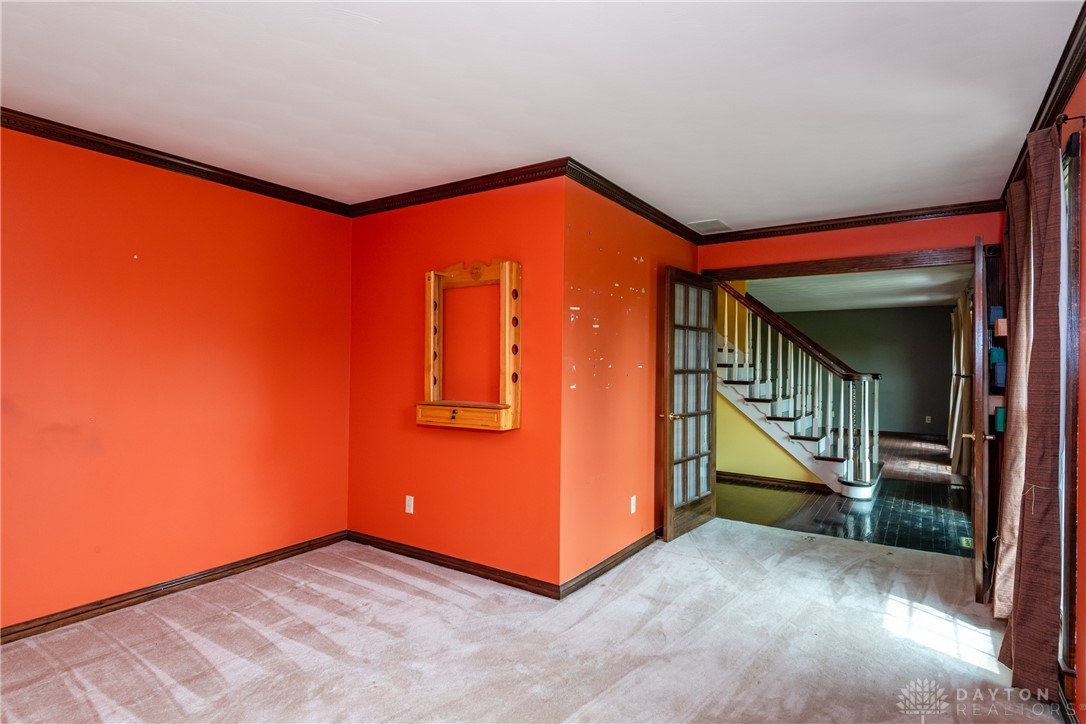 9981 Ridge Acres Lane Englewood, OH 45322 - Photo 20 of 73 An inviting room boasts carpet flooring, crown molding, and direct access to a well-crafted staircase.