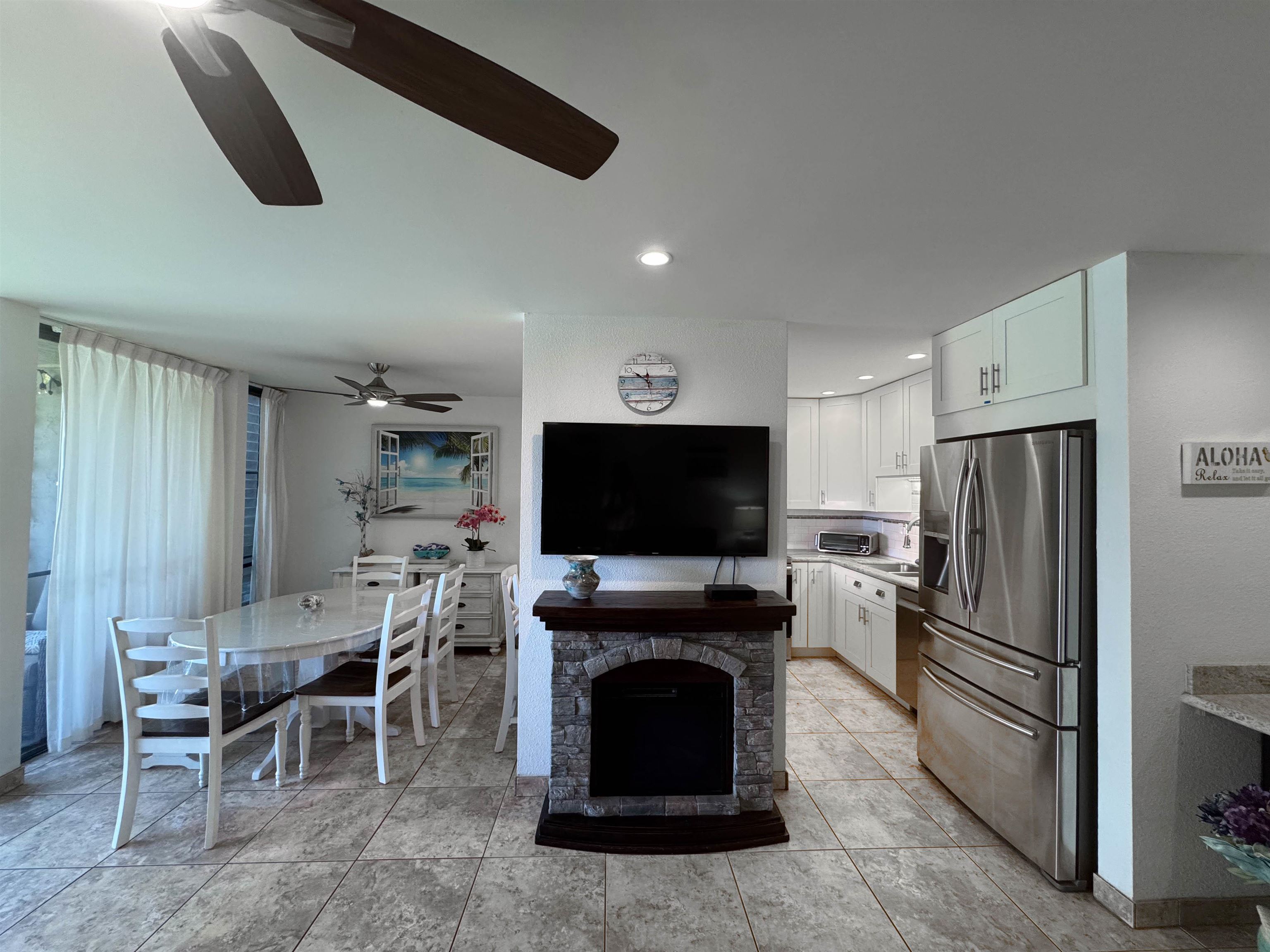 483 South Kihei Road, Unit 115 Kihei, HI 96753 - Photo 11 of 36 a living room with furniture a flat screen tv and a refrigerator