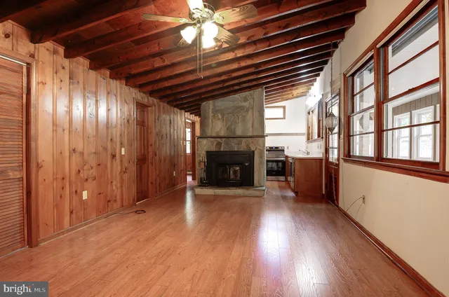 a view of an empty room with wooden floor fireplace and a window