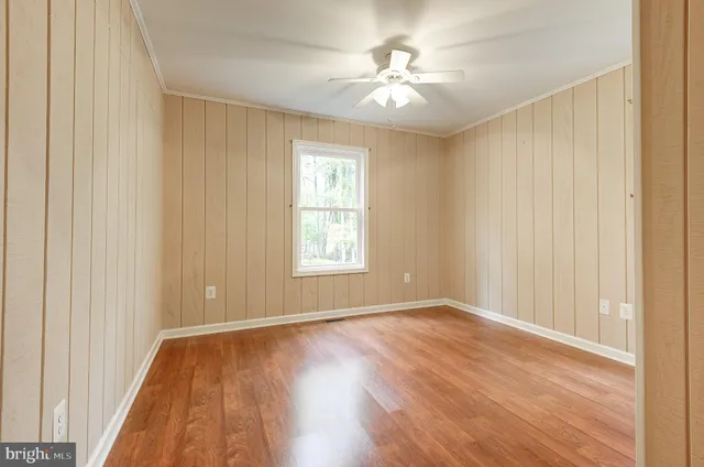 an empty room with wooden floor chandelier fan and windows