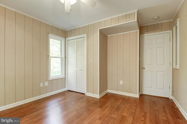 an empty room with wooden floor cabinet and windows