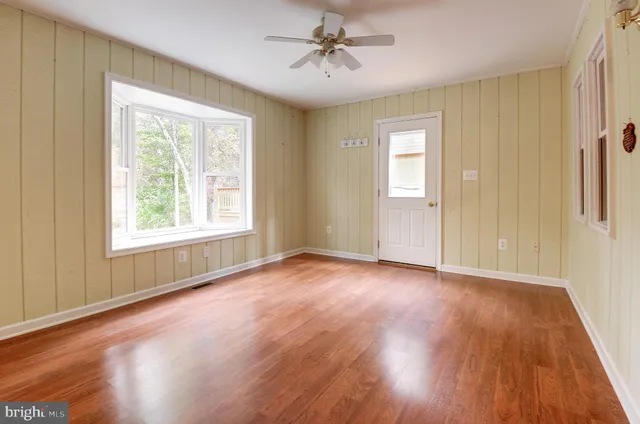 a view of an empty room with window and wooden floor