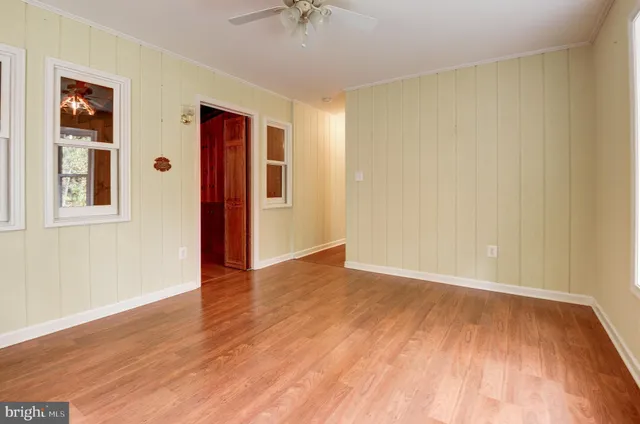 a view of an empty room with wooden floor and a window