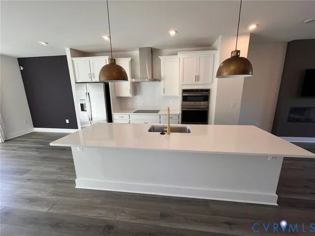 a kitchen with stainless steel appliances a refrigerator sink and wooden floor