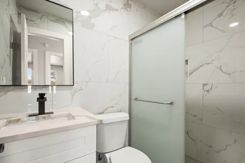 a living room with stainless steel appliances a refrigerator a stove top oven a sink and cabinets