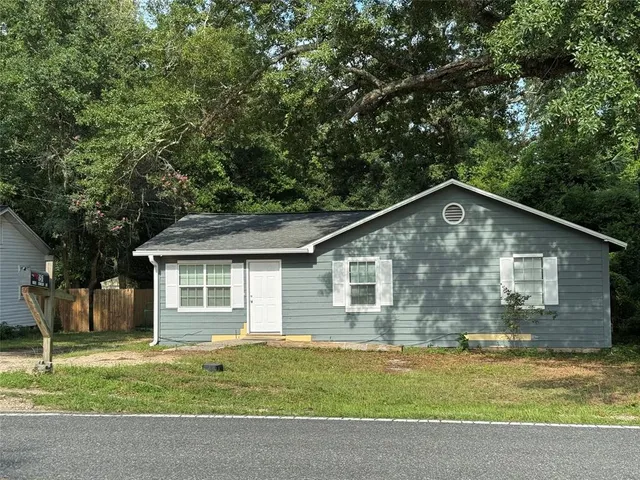 a view of a yard in front of a house with large trees