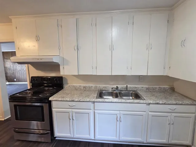 a kitchen with granite countertop white cabinets and a stove