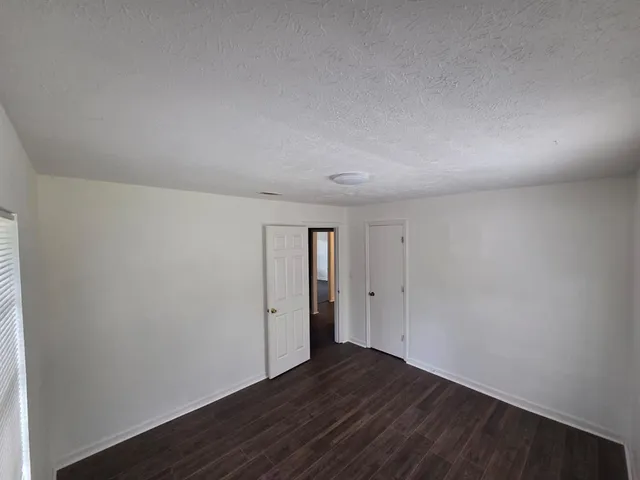 a view of an empty room with wooden floor and closet