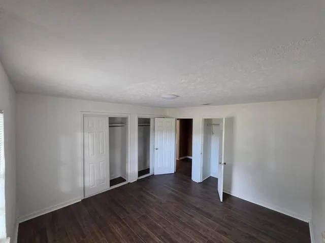 an empty room with wooden floor & windows and bathroom