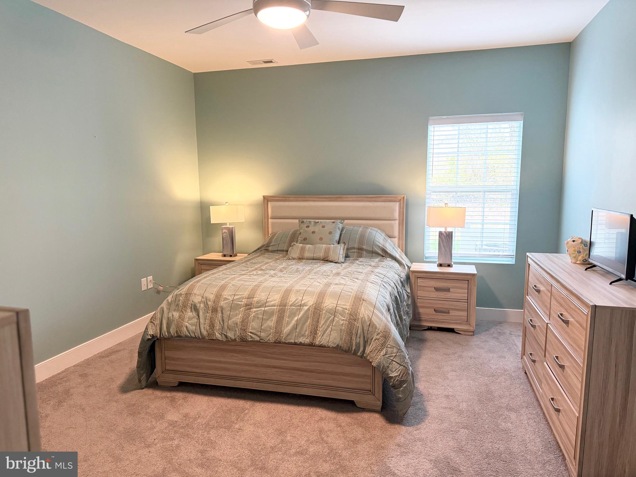 30609 Cedar Neck Road, Unit 3103 Ocean View, DE 19970 - Photo 20 of 39 a spacious bedroom with a bed and a chandelier