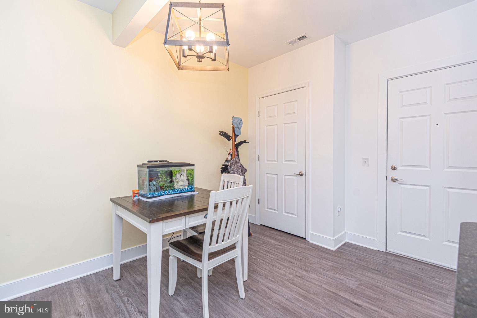 30609 Cedar Neck Road, Unit 3103 Ocean View, DE 19970 - Photo 4 of 39 a dining room with wooden floor a chandelier a wooden table and chairs