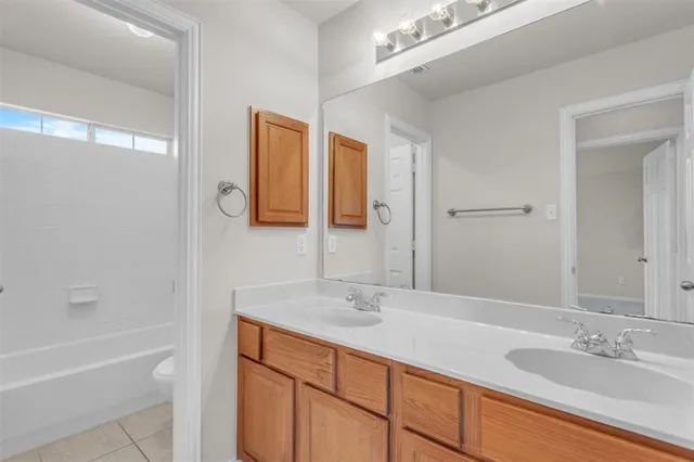 a bathroom with a granite countertop sink mirror and a bath tub