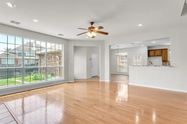 a view of an empty room with window and wooden floor