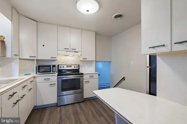 an empty room with chandelier fan and windows