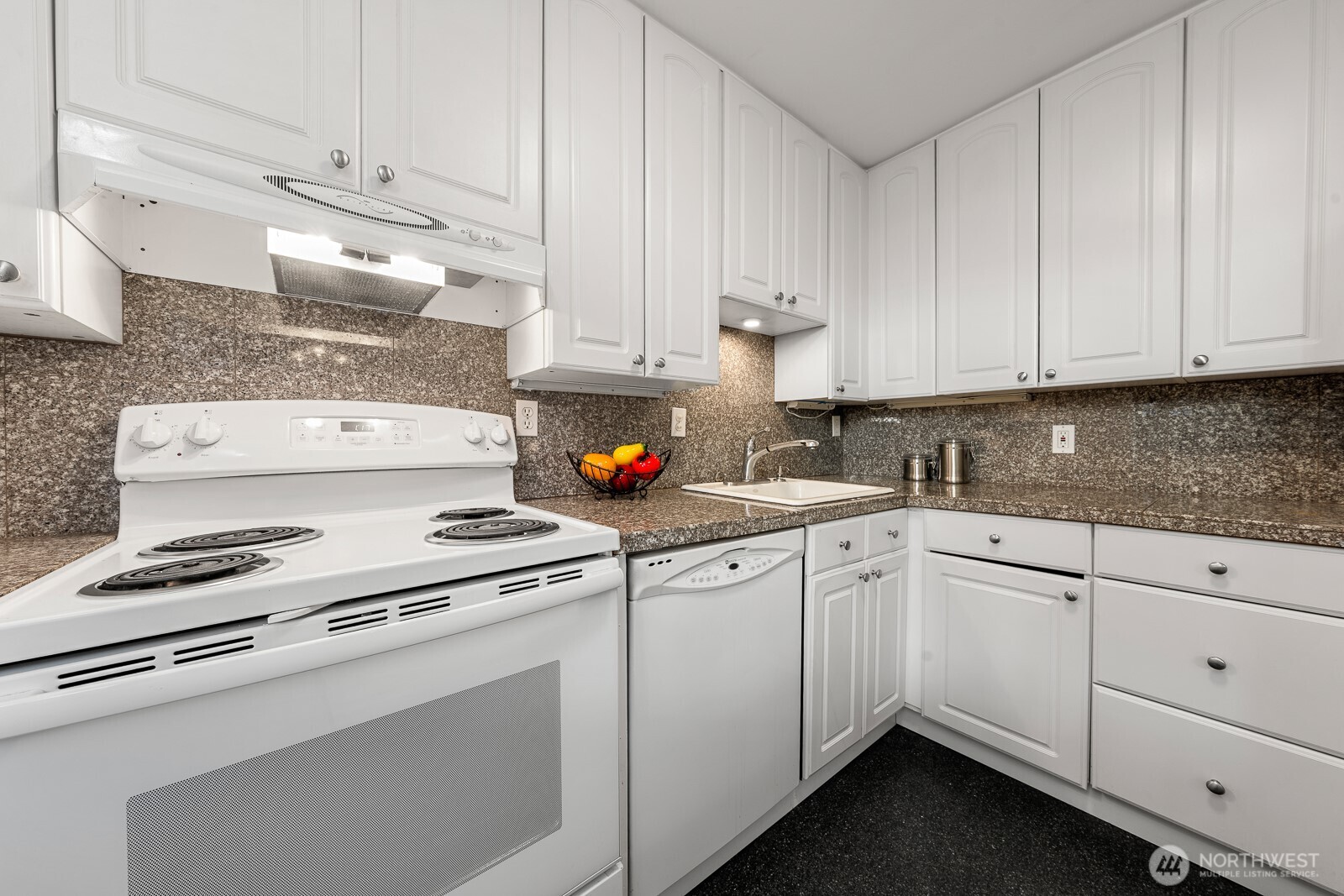 912 3rd Avenue West, Unit 101 Seattle, WA 98119 - Photo 10 of 25 a kitchen with granite countertop white cabinets and white appliances
