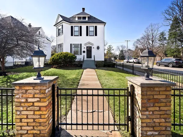 a view of a white house with a yard table and chairs