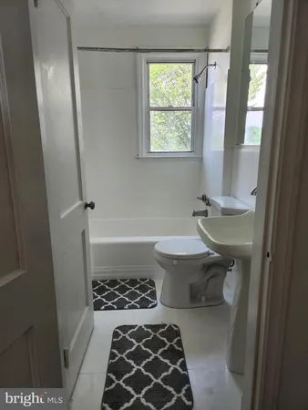 a bathroom with a sink a toilet a window and a bathtub