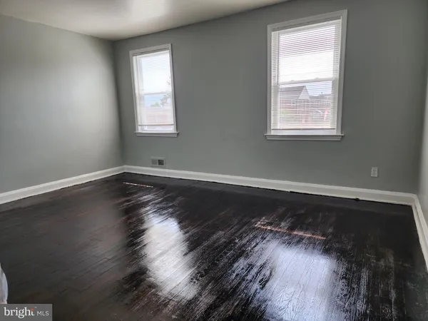 a view of wooden floor in an empty room with a window