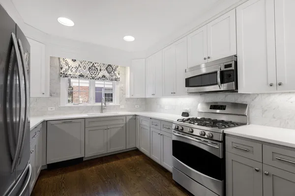 a kitchen with stainless steel appliances white cabinets and a stove top oven