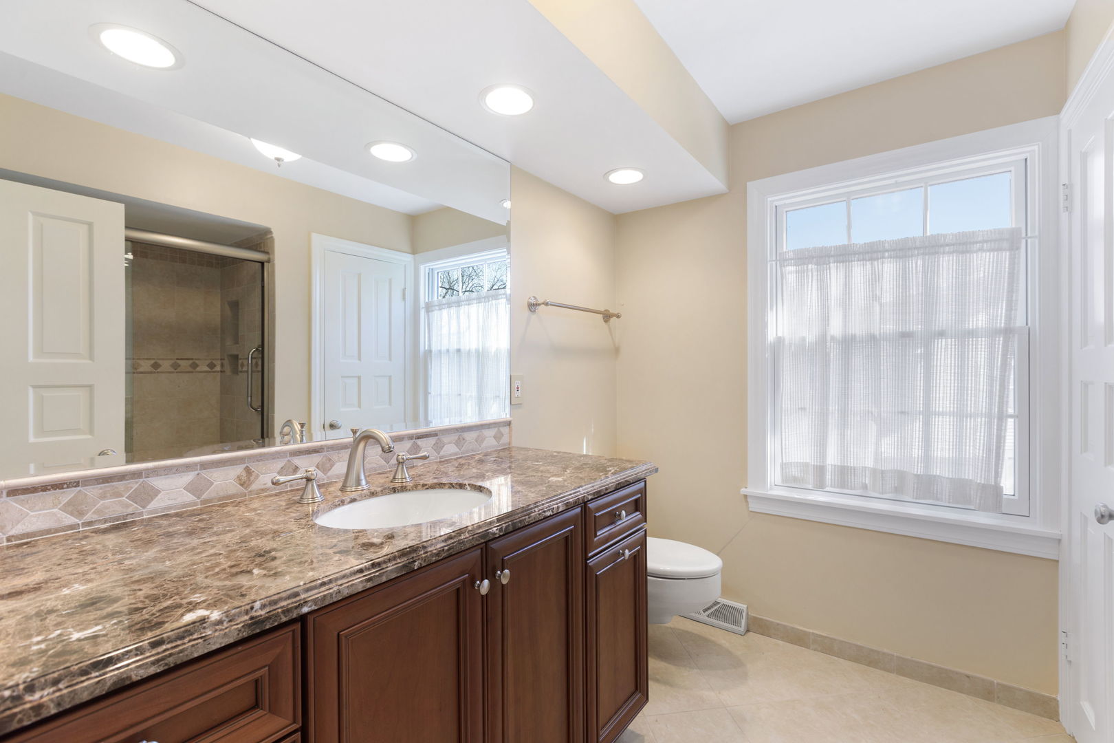1115 Golfview Lane Glenview, IL 60025 - Photo 29 of 46 a bathroom with a granite countertop sink a toilet a mirror and a window