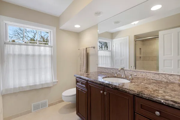 a bathroom with a granite countertop sink a toilet and a mirror