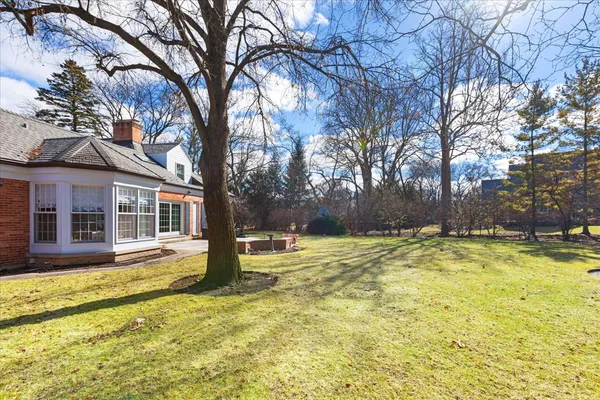 a view of a house with snow on a yard and large trees