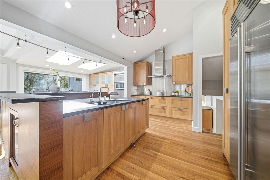 54 Oakvale Road Newton, MA 02468 - Photo 5 of 42 a large kitchen with stainless steel appliances granite countertop a large kitchen island a refrigerator a stove a oven and a large window with wooden floors