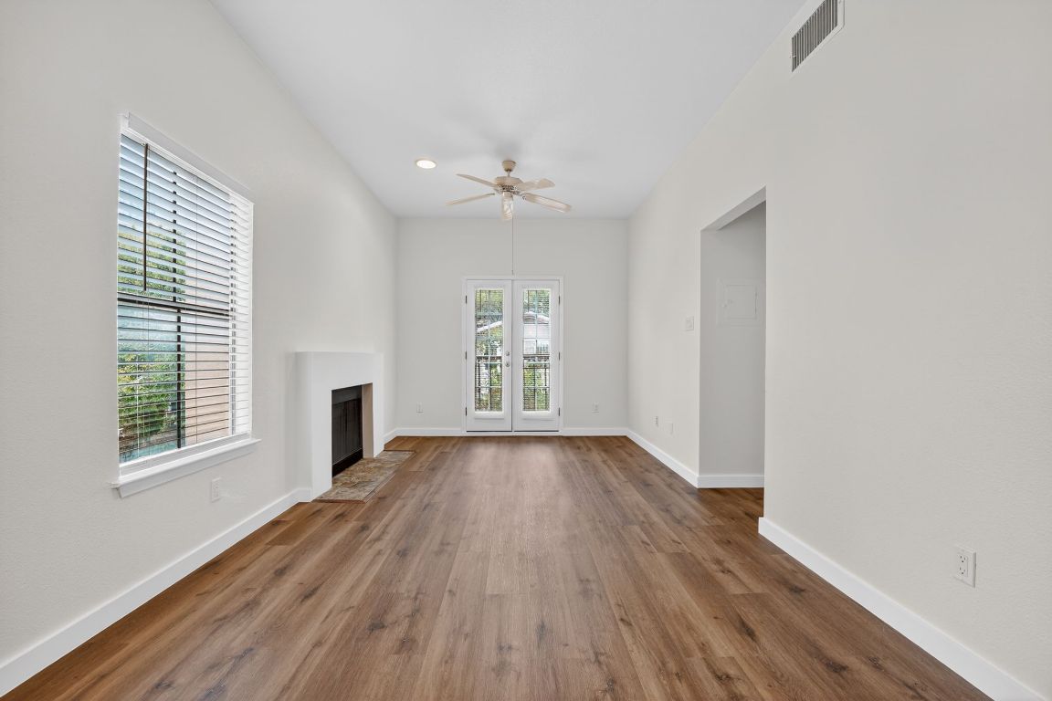 712 Graham Place, Unit 201 Austin, TX 78705 - Photo 13 of 36 an empty room with wooden floor chandelier fan and windows