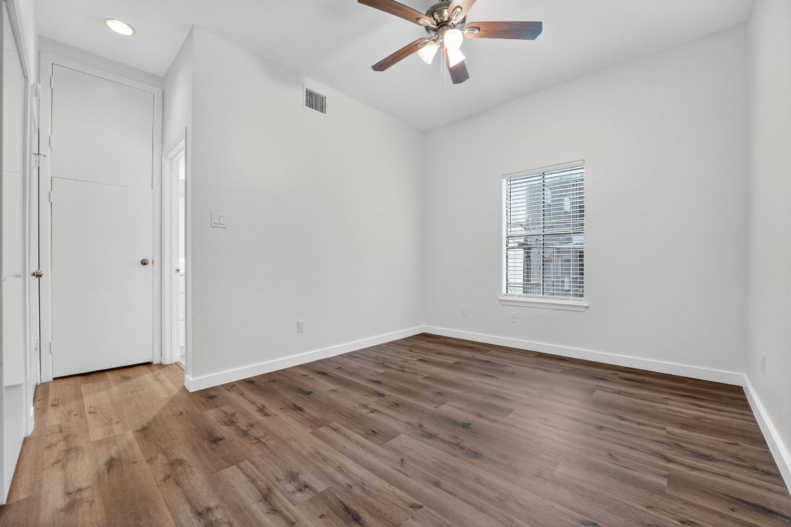 712 Graham Place, Unit 201 Austin, TX 78705 - Photo 20 of 36 an empty room with wooden floor chandelier fan and windows