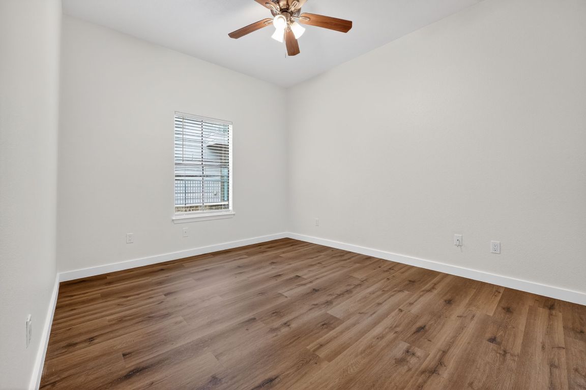 712 Graham Place, Unit 201 Austin, TX 78705 - Photo 21 of 36 an empty room with wooden floor chandelier fan and windows