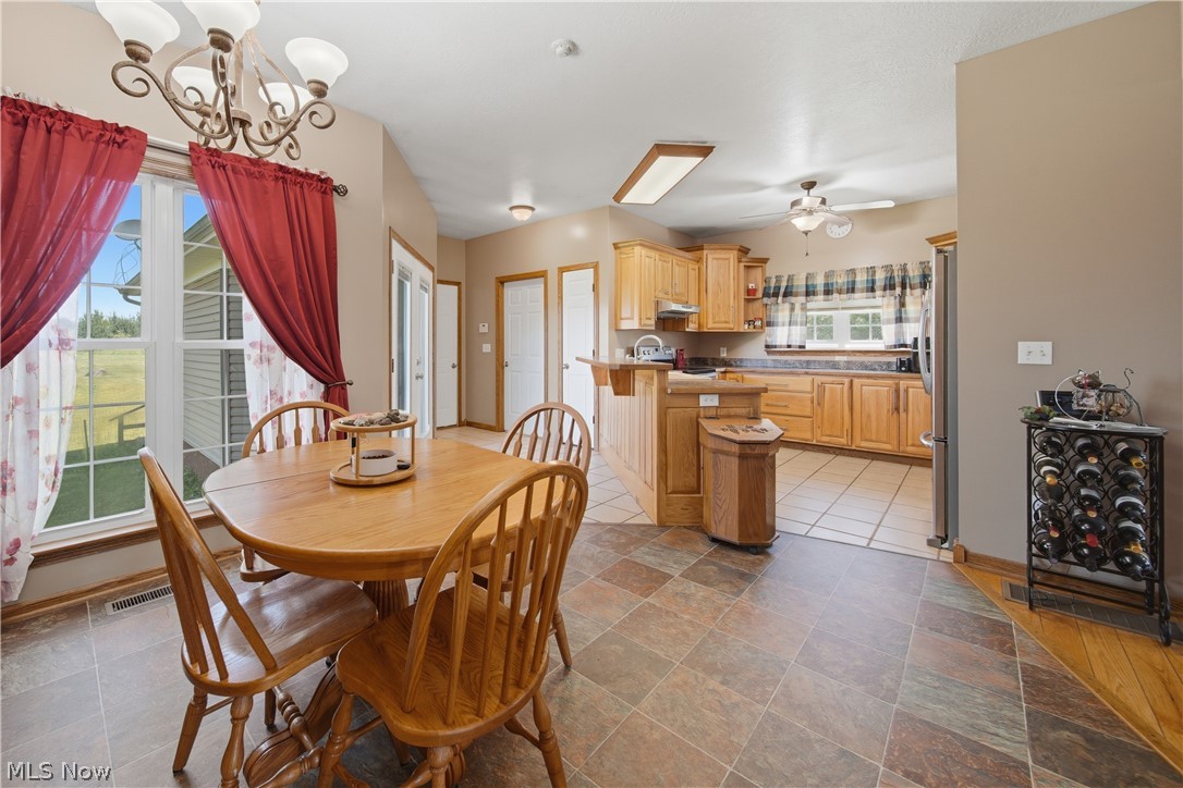 12159 Lawndell Road Southwest Beach City, OH 44608 - Photo 13 of 49 Open concept kitchen and dining area featuring light wood cabinetry, a breakfast bar, and mixed tile and wood-finish flooring
