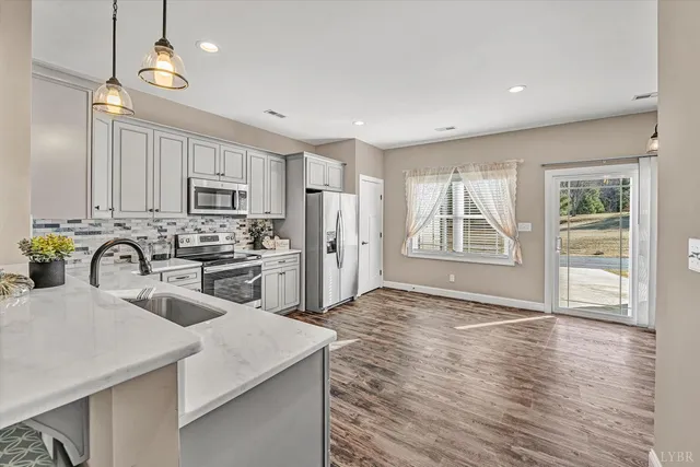 a large white kitchen with a refrigerator a sink dishwasher a stove and white cabinets with wooden floor