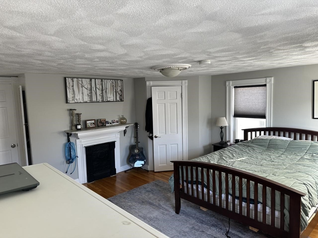 123 Faneuil Street, Unit 2 Boston, MA 02135 - Photo 8 of 12 a bedroom with furniture and a fireplace