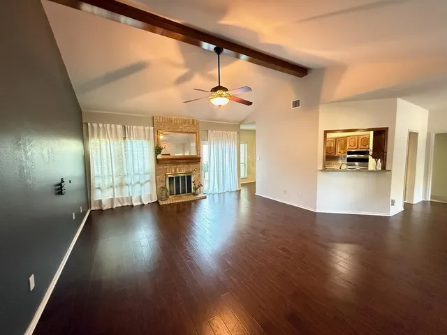 an empty room with wooden floor fireplace and windows