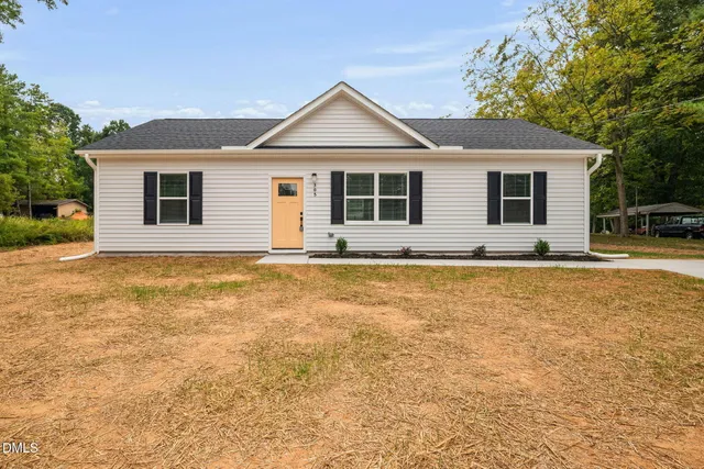 a front view of house with yard and trees in the background