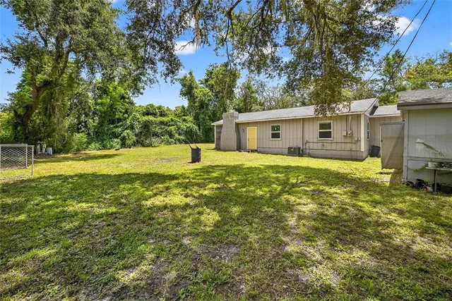 a view of a house with a big yard and large trees