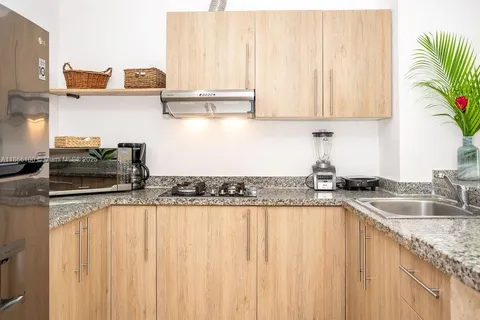 a kitchen with stainless steel appliances granite countertop a sink a stove and a wooden cabinets