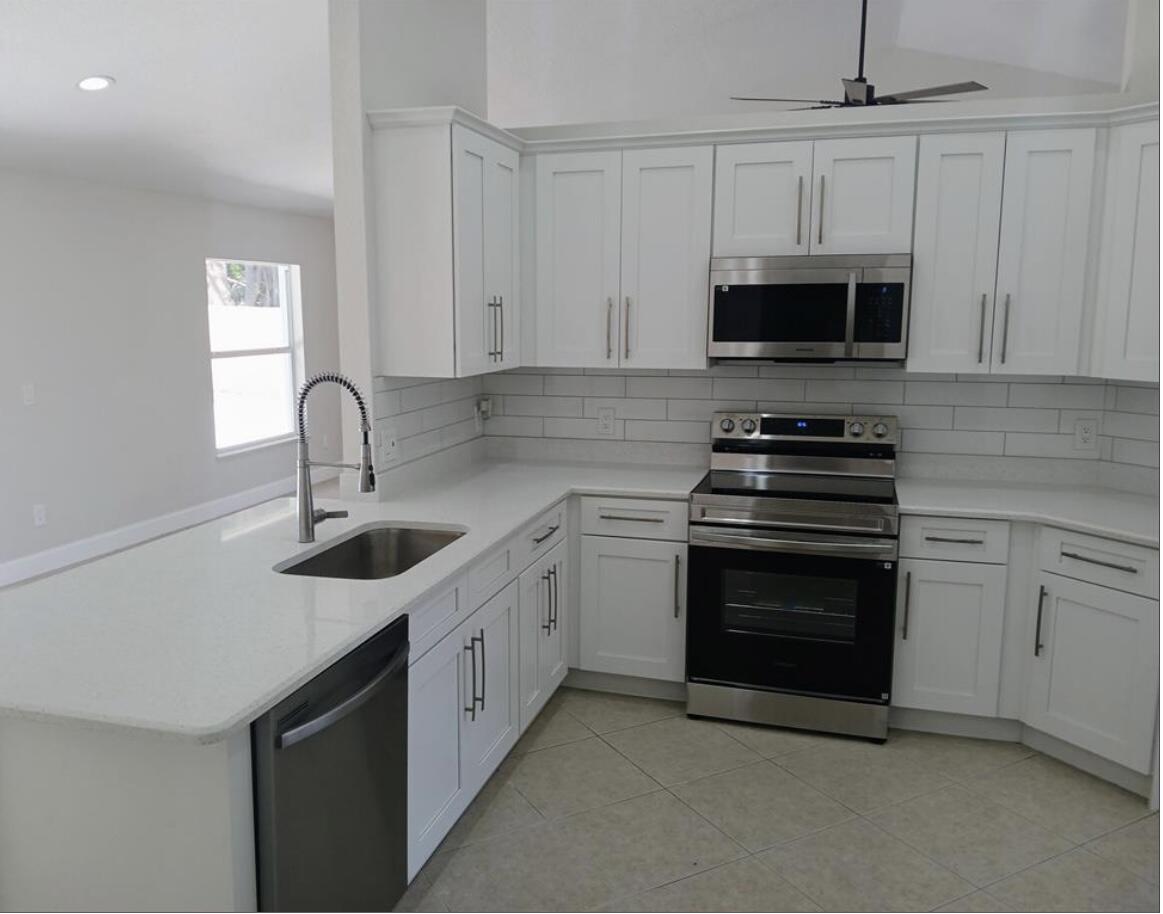 3450 Southwest Martin Street Port St. Lucie, FL 34953 - Photo 3 of 7 a kitchen with stainless steel appliances granite countertop a sink dishwasher a stove and a microwave oven with cabinets