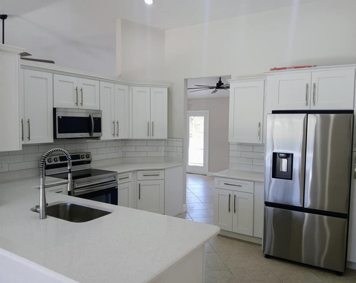 3450 Southwest Martin Street Port St. Lucie, FL 34953 - Photo 4 of 7 a kitchen with stainless steel appliances a refrigerator stove and microwave