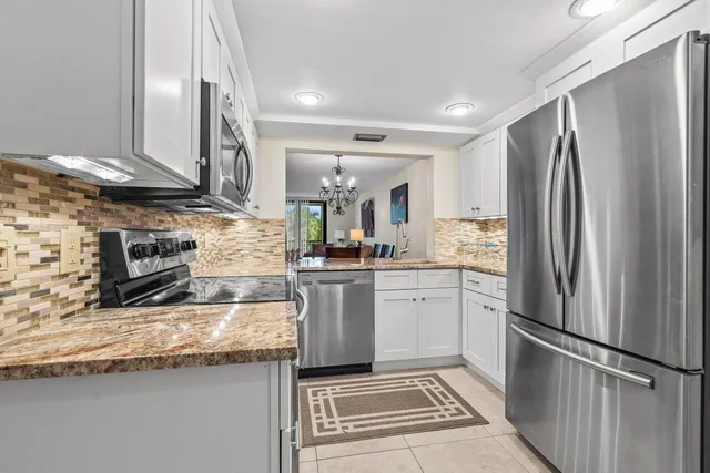 a kitchen with stainless steel appliances granite countertop a refrigerator a stove and a sink