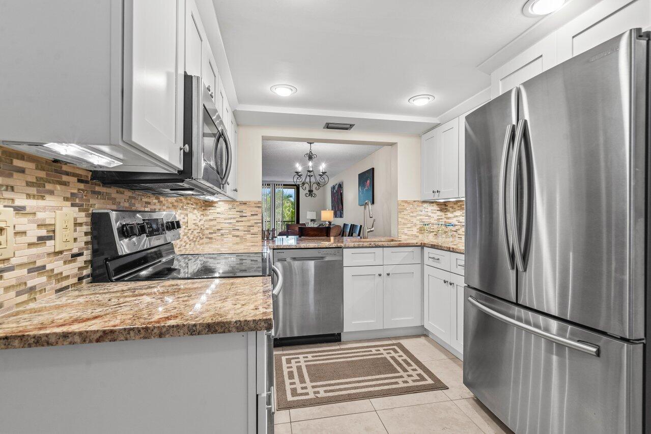 2070 Homewood Boulevard, Unit 4140 Delray Beach, FL 33445 - Photo 5 of 28 a kitchen with stainless steel appliances granite countertop a refrigerator a stove and a sink